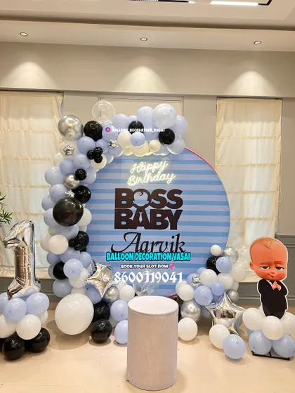 Aarvik's Boss Baby first birthday. This modern setup features a striped round backdrop, a balloon garland, and a character cutout for a stylish party.