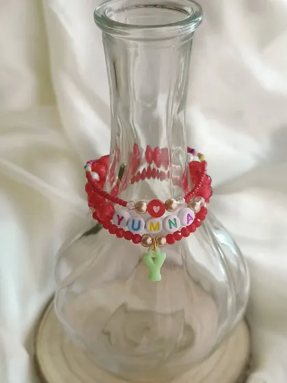 Our personalized red stack bracelet for Yumna, elegantly displayed in a glass vase to show off its details.
