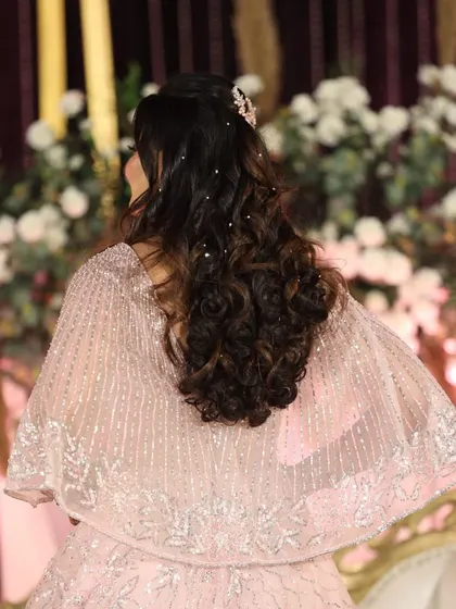 A view of the elegant hairstyle created for this reception look, with soft curls and delicate pearl accessories woven through.