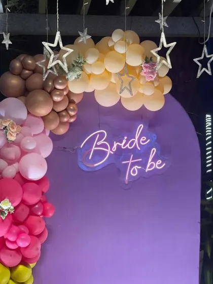 A close-up of the 'Bride to be' neon sign and the pastel-toned balloon garland from the terrace party setup.