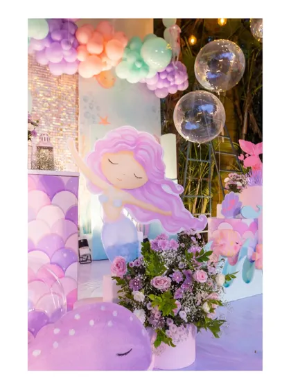 A beautiful mermaid cutout with flowing purple hair, placed next to a floral arrangement, adding an artistic touch to the underwater theme.