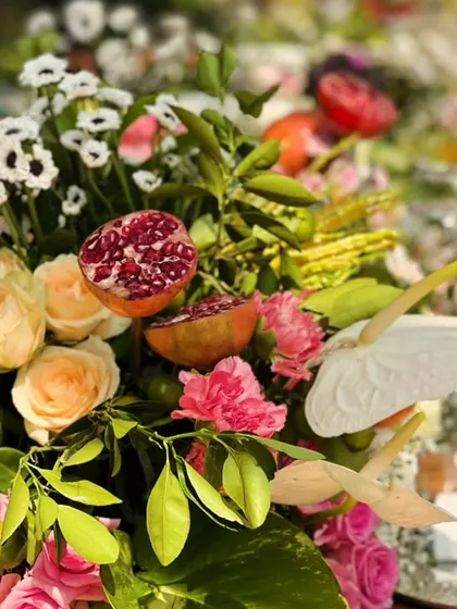 A lush floral centerpiece for a winter brunch, creatively incorporating fresh pomegranates among the roses for a pop of color and seasonal touch.
