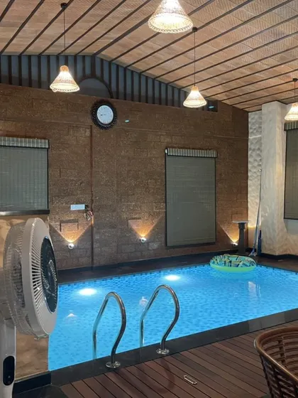 The same indoor pool area at night, where warm, layered lighting from pendant and wall fixtures creates an intimate and relaxing ambiance.