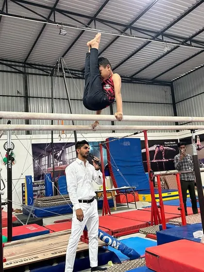 A gymnast holds a challenging L-sit variation on the parallel bars, demonstrating incredible core and shoulder strength.