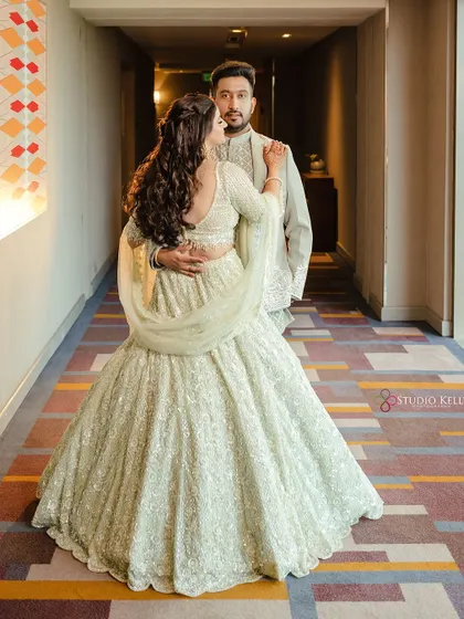 A back-shot of the couple, showing the beautiful details of the bride's lehenga and hairstyle.