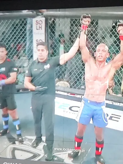 A champion's moment. One of our fighters celebrating his win inside the cage, a culmination of months of relentless training and preparation.