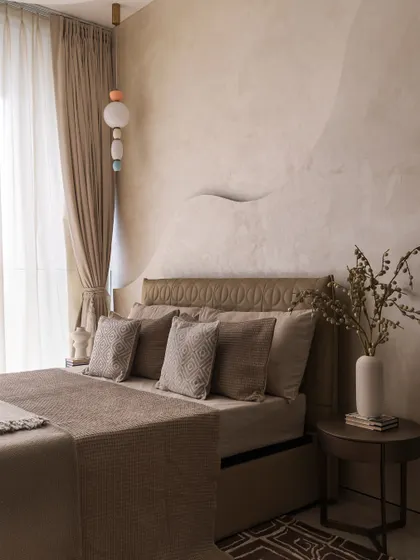 This bedroom showcases the art of layering textures for depth. A sculptural wave detail on the wall, an embossed leather headboard, and a mix of textiles on the bed create a rich, inviting, and tactile experience.