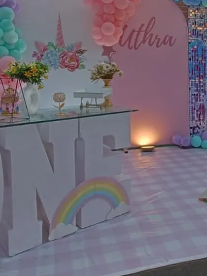 A detailed shot of a unicorn-themed first birthday. The large 'ONE' prop and custom-printed plinths create a cohesive and magical look.