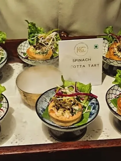 These Spinach Ricotta Tarts are a savory and elegant appetizer. The bite-sized pastries are filled with a creamy mixture of spinach and ricotta cheese, garnished with microgreens, and served on a wooden tray.