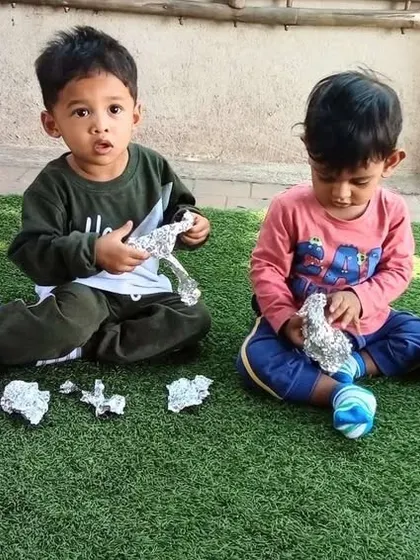 A sensory play session with aluminum foil. Toddlers explore the unique texture and sound of the material, which is a great way to stimulate their senses and curiosity.