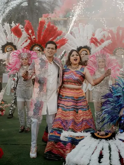 A joyous shot of the couple at their carnival, surrounded by performers. The colorful feathers and pyrotechnics add to the celebratory atmosphere.