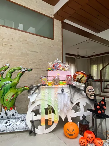 A spooky Halloween candy cart. The cart is decorated with a zombie hand, a witch's hat, and other scary props, and filled with treats for a "trick or treat" station.