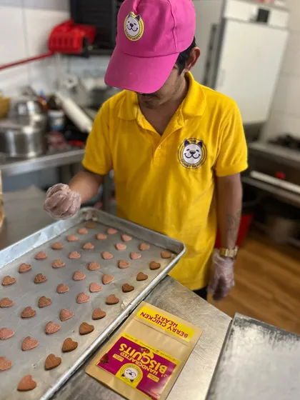 Our baker carefully prepares a tray of heart-shaped berry biscuits, ready to be baked for Valentine's Day. Each one is made by hand.