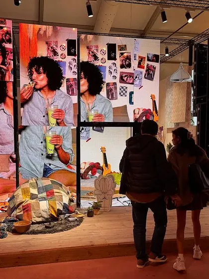 Visitors interacting with the 'Goblin Mode' installation. The space is designed to be a tactile and sensorial landscape, where hand-tufted textures and soft crochet forms invite imagination and a sense of whimsical, cocooned coziness.