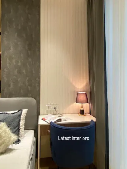 A cozy corner in a modern luxury bedroom, featuring a small study desk with a blue chair. The combination of dark textured wallpaper and warm lighting creates an intimate and glamorous feel.