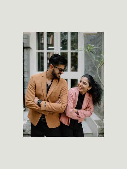 A sweet, framed shot of a couple in modern attire, laughing together. The simple border gives it a clean, contemporary feel, suitable for social media announcements.