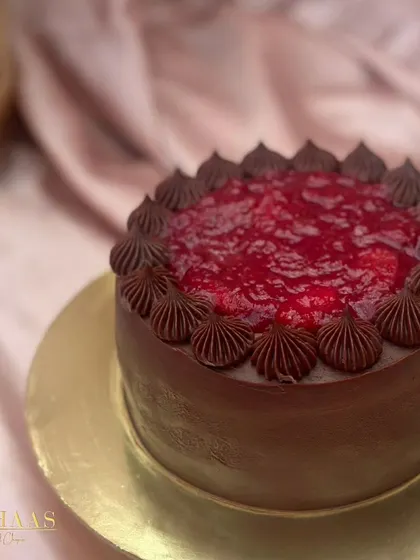 A rich chocolate cake crowned with a vibrant, glossy raspberry compote and bordered by delicate chocolate piping. The contrast of deep chocolate and tart berry is simply divine.
