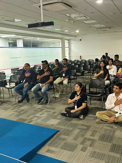 Participants in a mindfulness meditation session placing a hand on their heart, a practice to cultivate self-compassion and awareness.