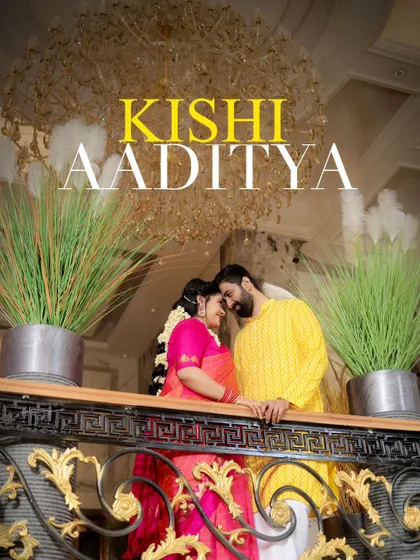 A majestic portrait of Kishi and Aaditya on a balcony, framed by lush plants and a grand chandelier.
