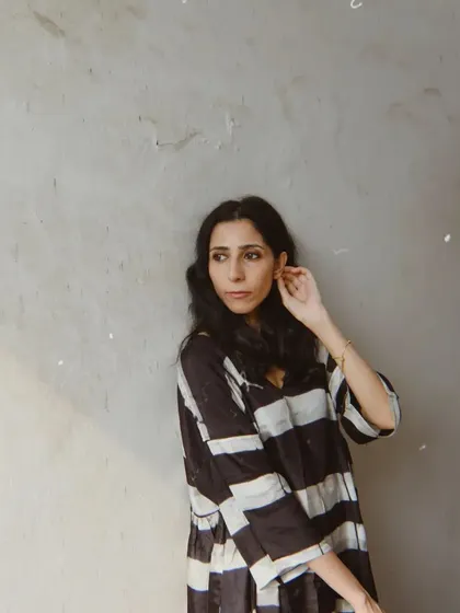 A quiet moment against a textured grey wall for House of Wandering Silk. The simplicity of the shot highlights the beauty of the garment.