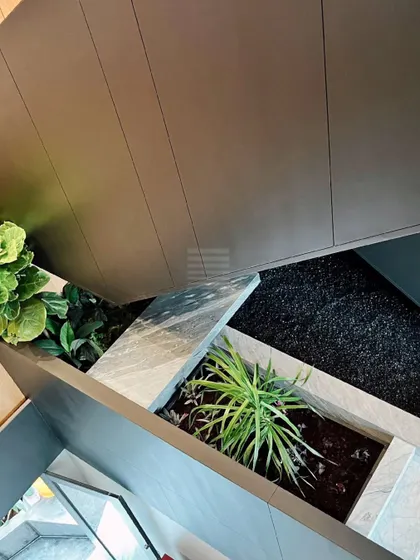 A detail of a contemporary villa lobby, where a curated planter box introduces a biophilic element. The design juxtaposes the clean lines of the architecture with the organic forms of the plants, reinforcing the connection between nature and design.