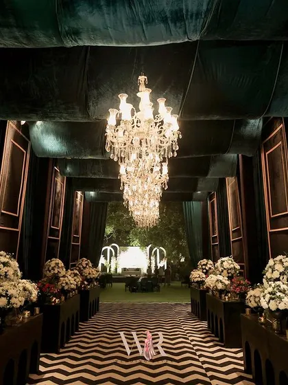 First impressions are everything. I designed this dramatic entrance with bold, black and white chevron flooring, framed by deep teal velvet drapes and a procession of crystal chandeliers, promising guests an evening of modern noir allure from the moment they arrived.