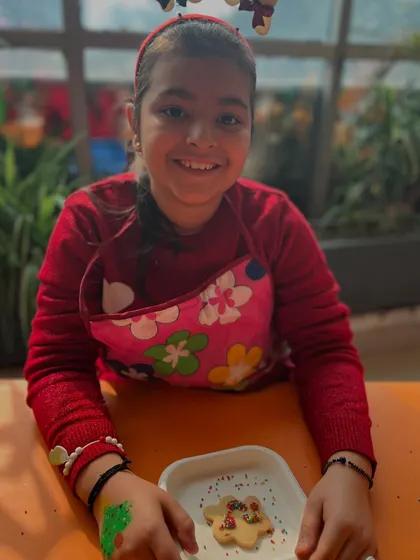 An older participant smiles proudly with her decorated cookie. Our workshops are designed to be fun for a range of ages.