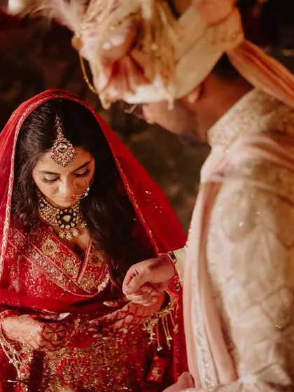 A traditional moment from an Indian wedding ceremony, where the groom ties the sacred thread. The focus on their hands and the ritual makes this a powerful, symbolic image.