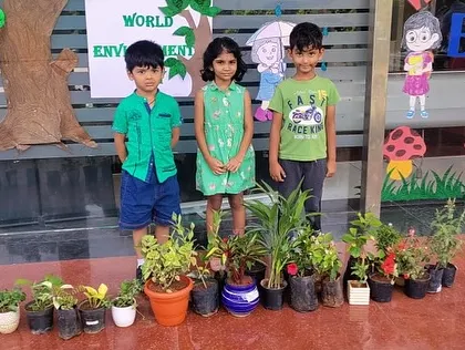 Three young students stand proudly with the collection of saplings they helped plant, learning about their role in protecting nature.
