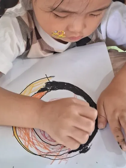 This child is coloring in the concentric circles representing the Earth's core, mantle, and crust, a great way to learn about geology through art.