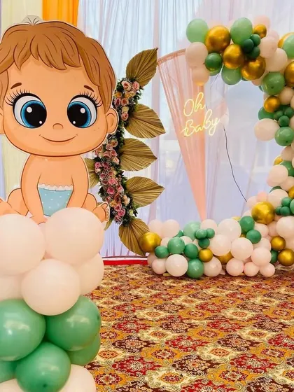 Adding a playful touch, this setup includes a cute, cartoon-style baby cutout on a balloon pillar. It pairs perfectly with the green, white, and gold balloon ring backdrop, making the celebration fun and memorable for all your guests.