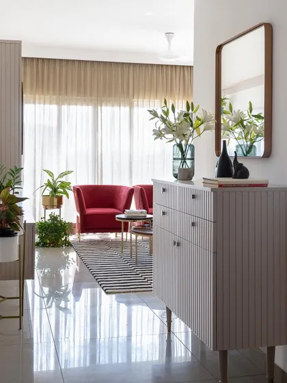 Designed for a professional golfer, this living room is a space to unwind. A calming pastel color scheme is energized by bold red accent chairs and a graphic striped rug, creating a perfect balance of style and comfort.