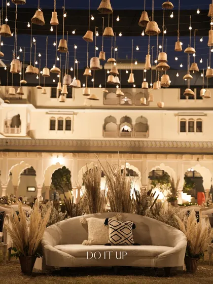 The seating area for the boho sangeet, with a comfortable couch set against the backdrop of the beautifully lit Jaipur palace. The hanging terracotta bells added a unique, artisanal touch.