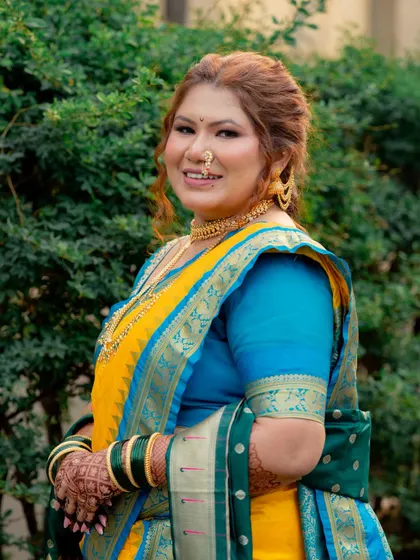A close-up portrait showcasing the bride's soft makeup and traditional gold jewelry. The look is timeless, elegant, and perfectly suited for a Maharashtrian wedding.