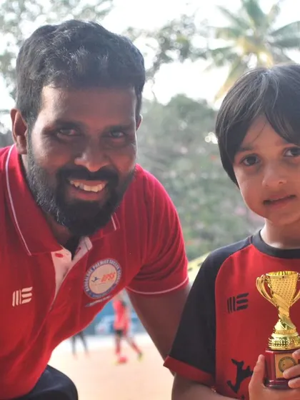 A coach and a young player share a smile with their trophy. These are the moments that build a lasting passion for the sport.