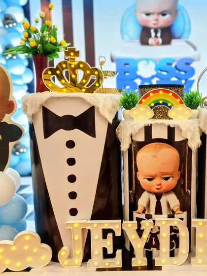 Details from Jeyden's Boss Baby party, including a tuxedo-print pedestal and a light-up name sign.