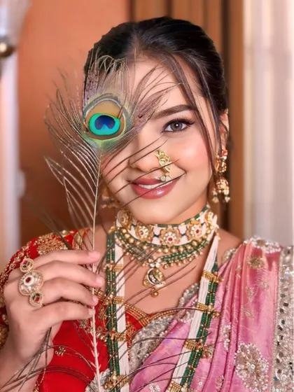 An artistic shot of a bride in a pink and red Nauvari saree. The peacock feather adds a touch of mystique to this traditional portrait.