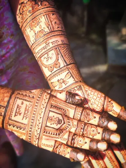 A close-up of a bridal design with the names of the couple, Pooja and Sagar, written in Devanagari script. Personalizing mehendi with names or dates is a wonderful way to make it special.