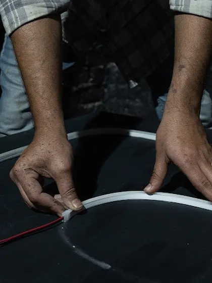 A close-up of my hands connecting the electrical components for the neon sign. This highlights the technical craft that goes into creating a large-scale light installation.