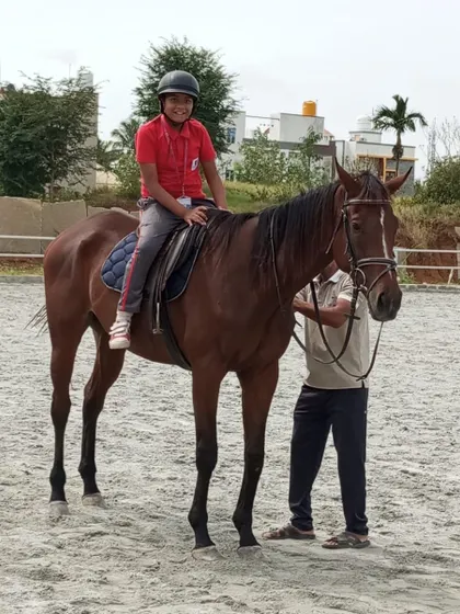 A student in his school uniform gets ready for his horse riding lesson, an activity that teaches responsibility and accountability.