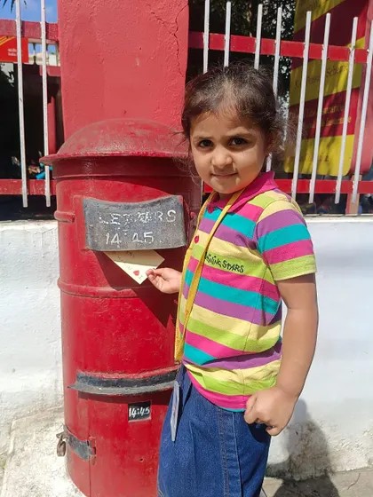 This young student smiles as she posts her letter, a simple act that taught a big lesson about communication.