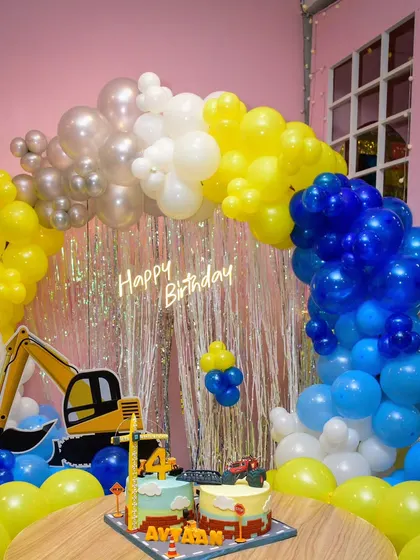 The complete construction party setup, featuring the amazing two-part cake perfectly integrated with the balloon arch and excavator decor.