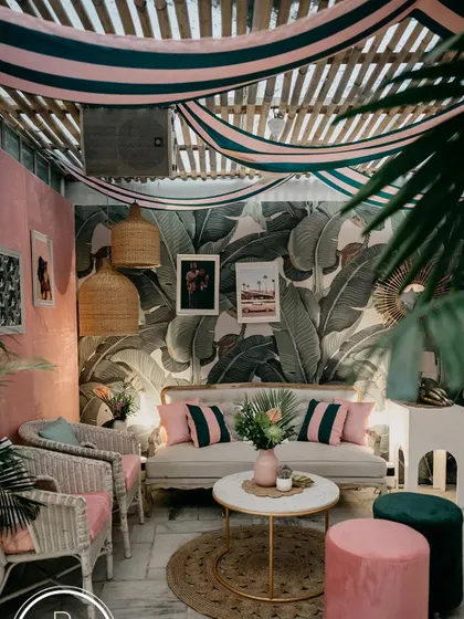A full view of the "Hotel California" themed lounge area. The combination of the striped ceiling drape, Martinique wallpaper, and curated furniture created a truly immersive retro vibe.