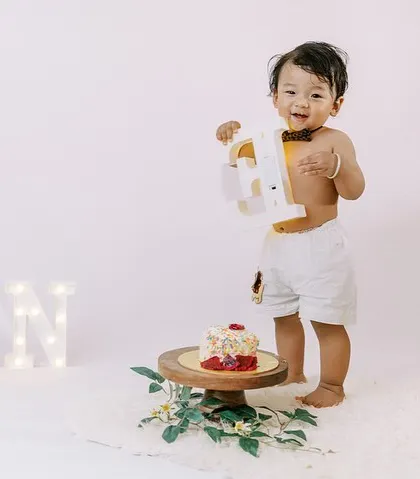 So much joy and excitement after the cake smash. This little guy is having a blast, holding up the number one from his birthday setup.