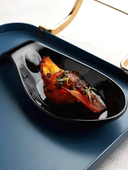 Our Hong Yu Wantons are a perfect bite-sized appetiser. These savoury dumplings are served in an elegant black spoon, drizzled with a flavourful sauce that balances sweet, spicy, and umami notes.