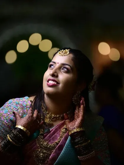 A dreamy reception look captured at night. The bride's makeup is designed to shine, with a beautiful highlight on her cheeks and a happy, upward gaze.