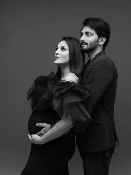 A hopeful and artistic black and white portrait. The couple looks up and away, as if dreaming of their future together, creating a beautifully composed and thoughtful maternity image.