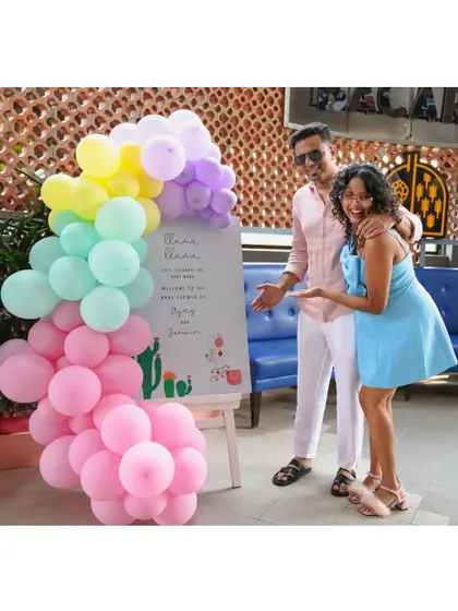 The happy clients posing with their Llama-themed welcome sign and a rainbow balloon arch.