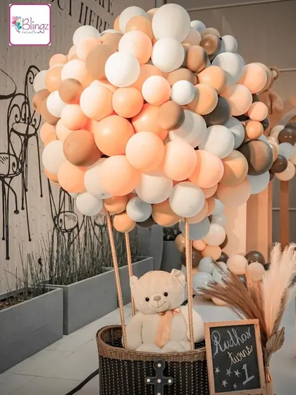 An adorable teddy bear sits in a hot air balloon made of balloons. This creative and cute prop was a highlight of a teddy bear themed first birthday, perfect for photos and adding a whimsical touch.