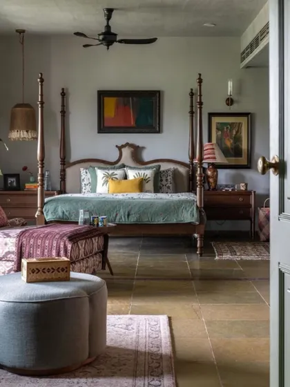 A glimpse into the master bedroom of the Dhaka residence, designed as a cultured and cozy retreat. The four-poster bed, sourced from India, is paired with a mix of textiles and art that reflect the clients' global journey. The stone flooring adds a rustic, earthy feel to this elegant space.
